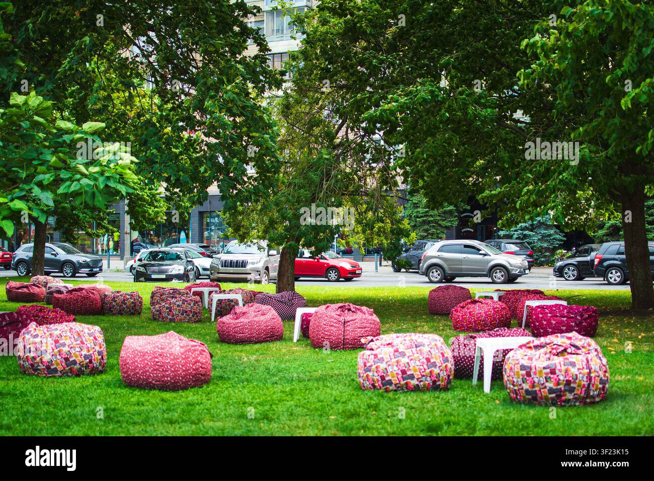 Ottomani morbidi per il relax, posizionati su un prato verde in un parco cittadino. Un concetto creativo di progettazione del paesaggio urbano per spazi pubblici, aree ricreative Foto Stock