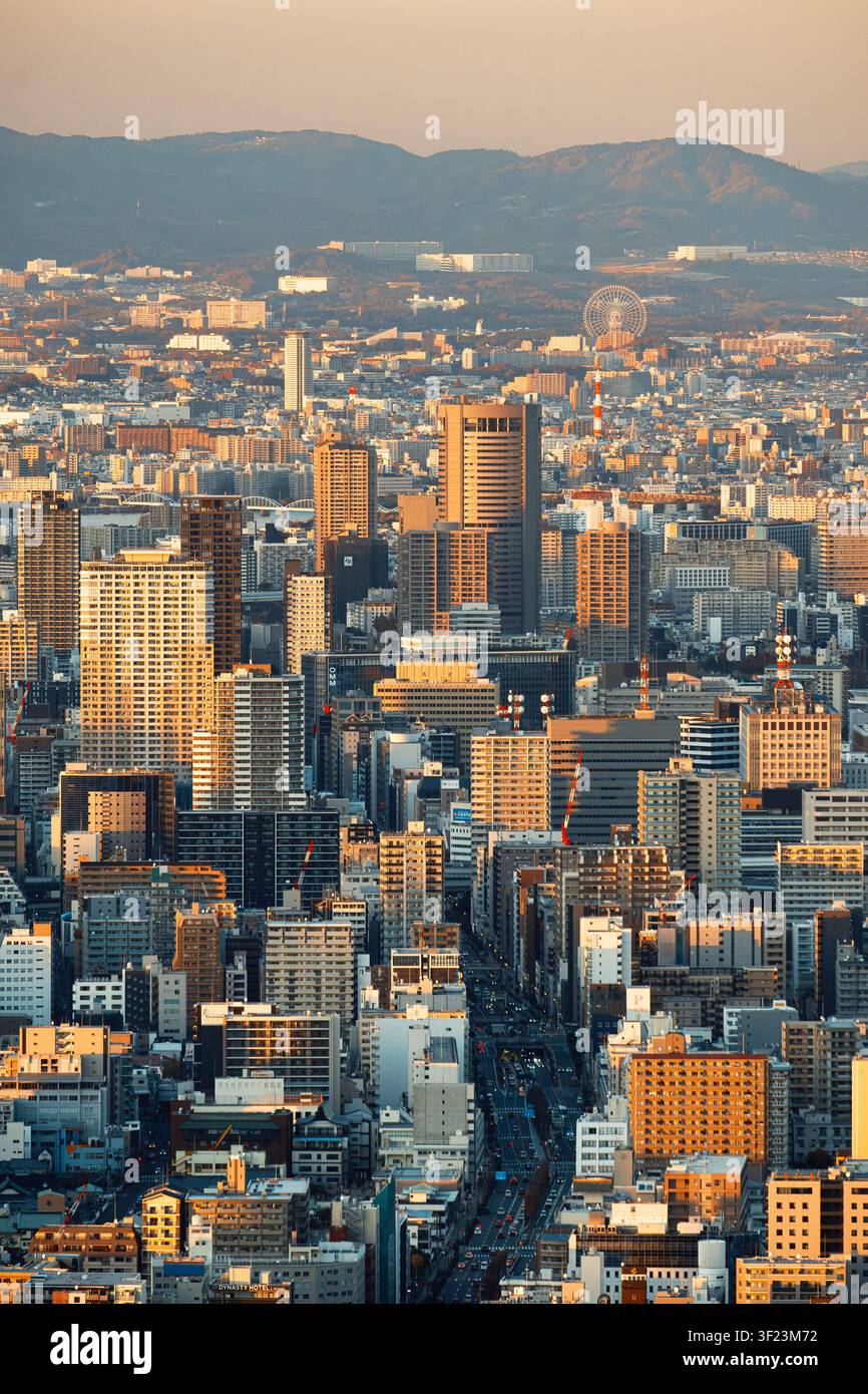 La città di Osaka si estende fino all'orizzonte in una fitta trama di grattacieli e strade, che brillano sotto l'ultimo calore del tramonto. Foto Stock