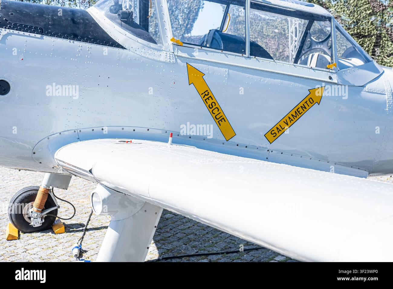 Dettaglio di un aereo vintage parcheggiato su ciottoli con segnalazioni di emergenza gialle brillanti Foto Stock