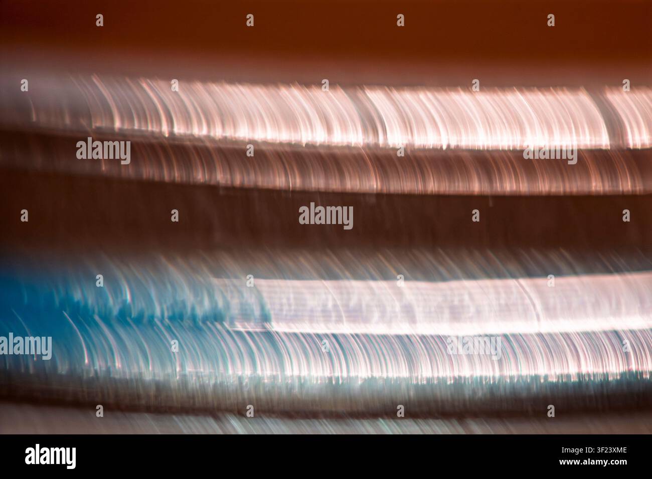 Strisce di luce orizzontali astratte con toni di rame e ciano che creano uno sfondo di movimento moderno. Foto Stock