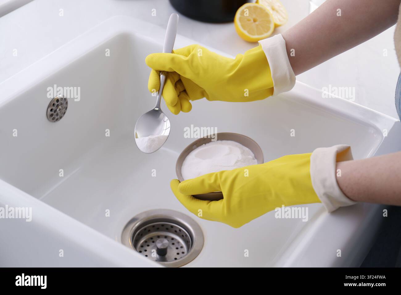 Donna che usa bicarbonato di sodio per disintasare lo scarico del lavandino, primo piano Foto Stock