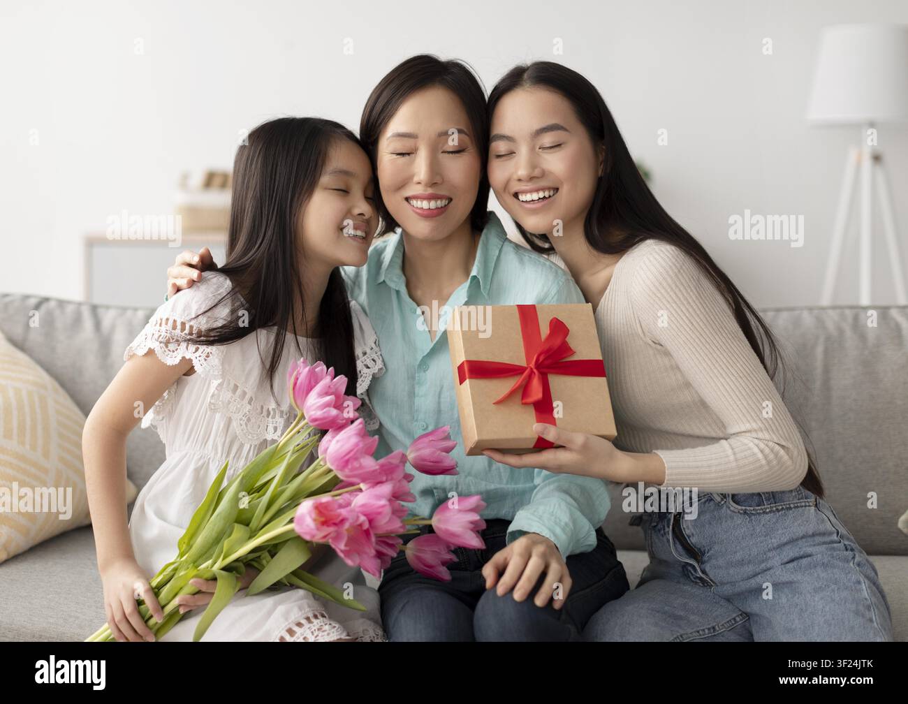 Madre asiatica felice con le figlie che celebra un'occasione speciale a casa, riceve un regalo Foto Stock
