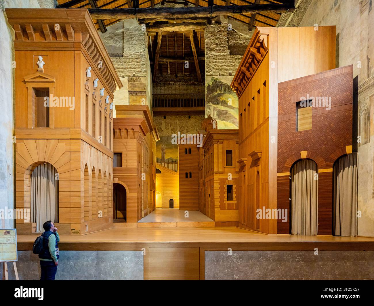 Uomo che osserva l'intricato allestimento fisso in legno di un capolavoro teatrale rinascimentale, con edifici fittizi che creano un'illusione di profondità e un Foto Stock