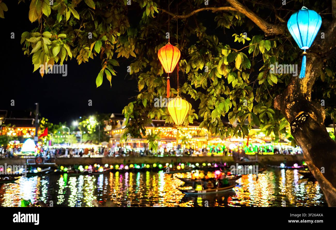 Dopo il tramonto, con luci colorate accese, passano barche fluviali con lanterne notturne, lungo il fiume luminosamente illuminato, che scorre attraverso la bella città storica. Foto Stock