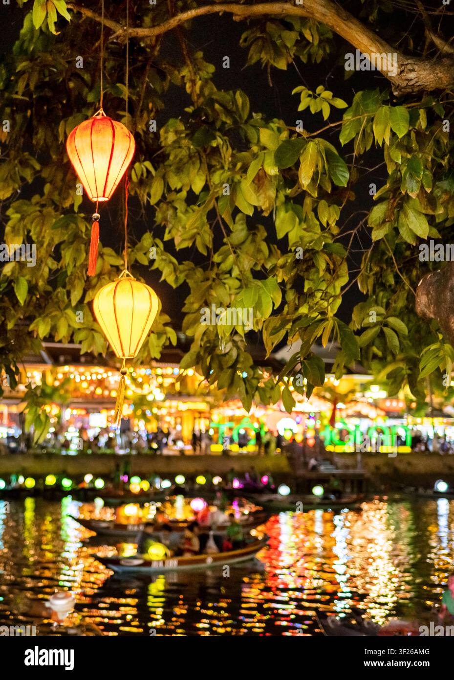 Dopo il tramonto, con luci colorate accese, passano barche fluviali con lanterne notturne, lungo il fiume luminosamente illuminato, che scorre attraverso la bella città storica. Foto Stock