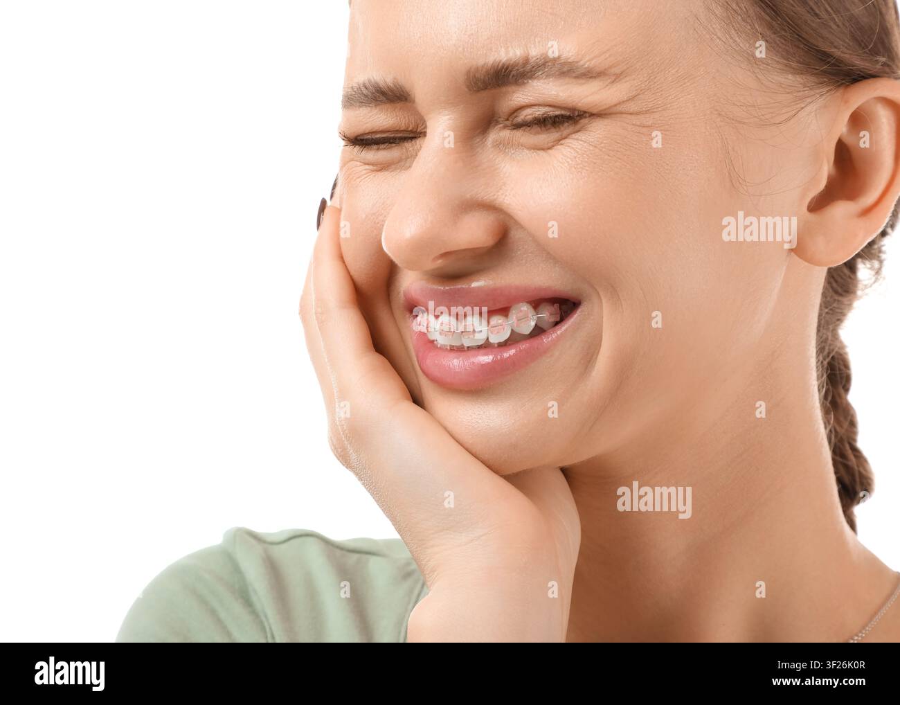 Giovane donna con apparecchio trasparente che sorride e si tocca la guancia, trattamento ortodontico e cura dentale Foto Stock