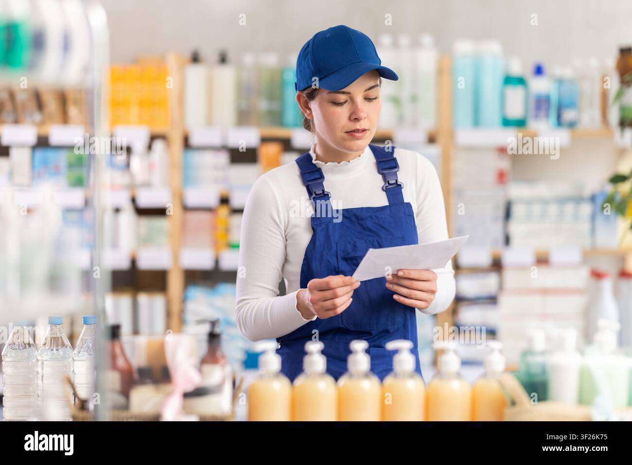 In farmacia, la donna costruttore con prescrizione medica guarda i casi esposti Foto Stock