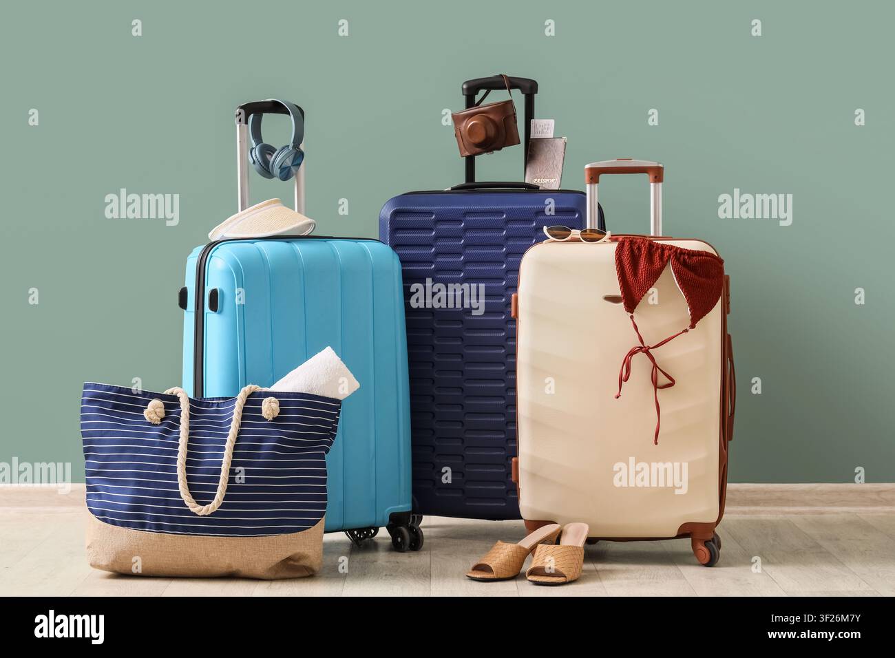 Tre valigie colorate con accessori da viaggio e articoli da spiaggia pronti per una vacanza estiva Foto Stock