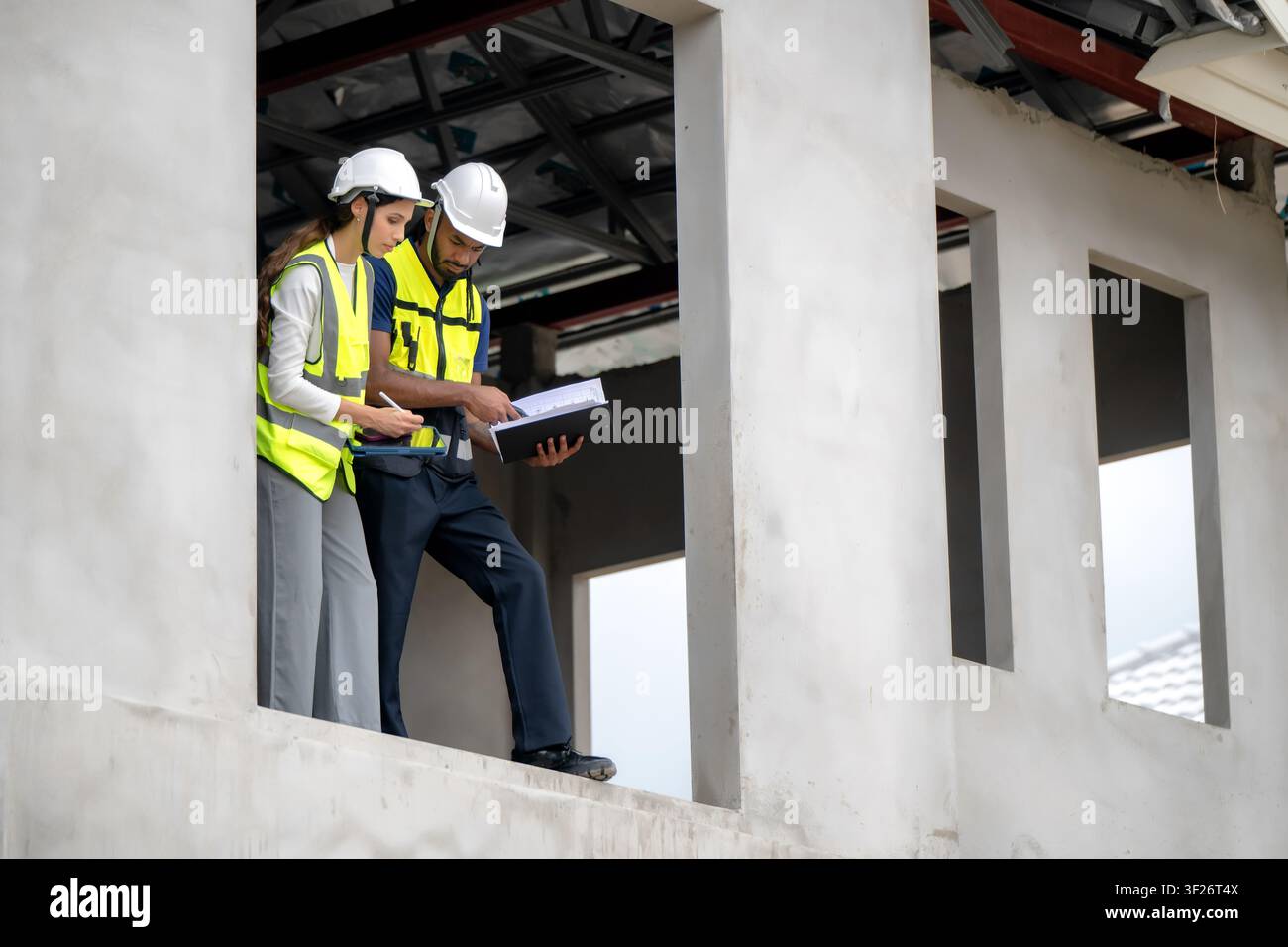 I responsabili edili controllano gli appunti sul balcone del secondo piano di una casa residenziale incompiuta durante il giorno, il concetto di gestione dei progetti e il tè Foto Stock