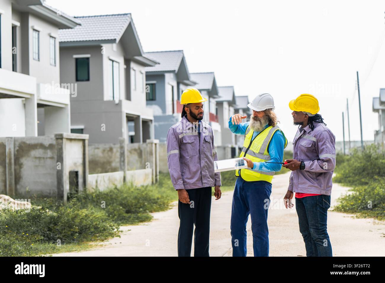 Gli ingegneri hanno discusso la preparazione per l'installazione di piccoli pannelli solari nelle aree di costruzione di villaggi residenziali per progetti di energia sostenibile e di improvvisazione Foto Stock