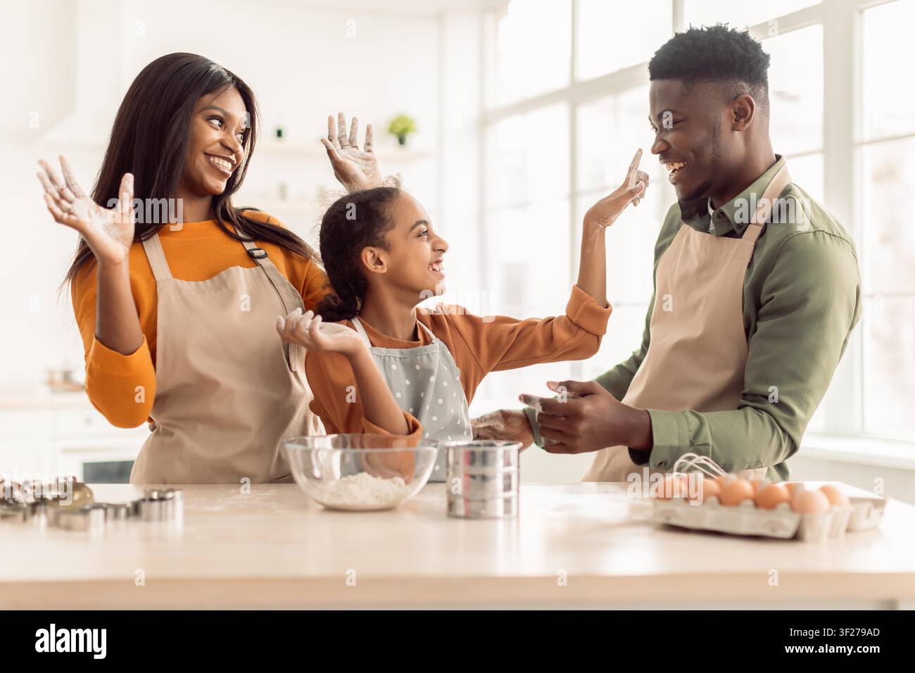 Felice famiglia afroamericana che cuoce insieme in cucina, godendosi del tempo di qualità Foto Stock