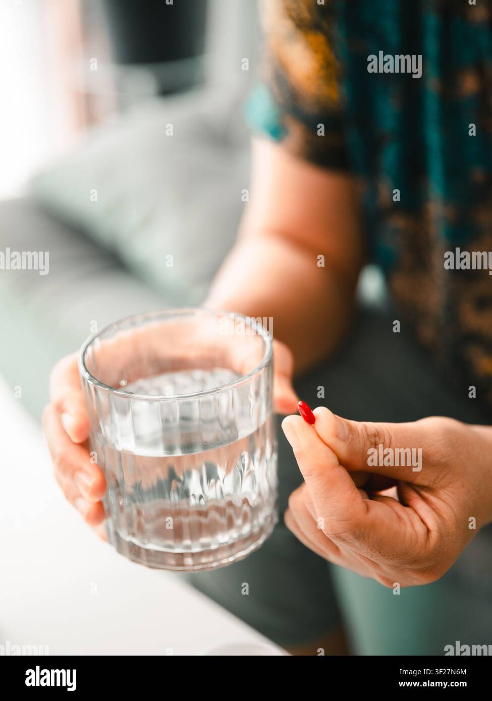 Prima di una donna asiatica che tiene una pillola rossa e un bicchiere d'acqua a casa, concetto di farmaci, assistenza sanitaria, prescrizione, integratore, trattamento e benessere Foto Stock