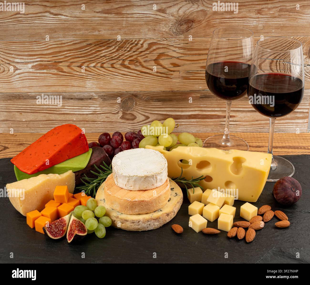 Piatto di formaggi vari colorati, piatto di gorgonzola giallo, bianco e blu con bicchiere di vino rosso, tagliere di formaggi, prodotti caseari tritati assortiti, m Foto Stock