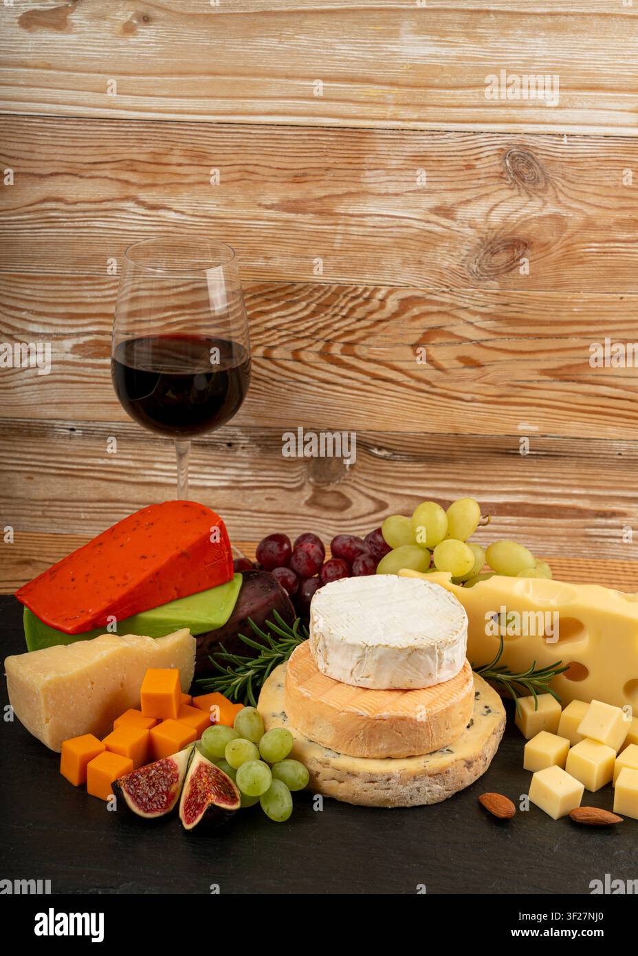 Piatto di formaggi vari colorati, piatto di gorgonzola giallo, bianco e blu con bicchiere di vino rosso, tagliere di formaggi, prodotti caseari tritati assortiti, m Foto Stock