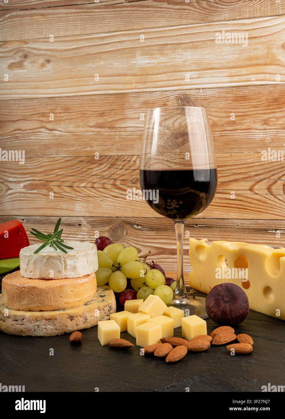 Piatto di formaggi vari colorati, piatto di gorgonzola giallo, bianco e blu con bicchiere di vino rosso, tagliere di formaggi, prodotti caseari tritati assortiti, m Foto Stock