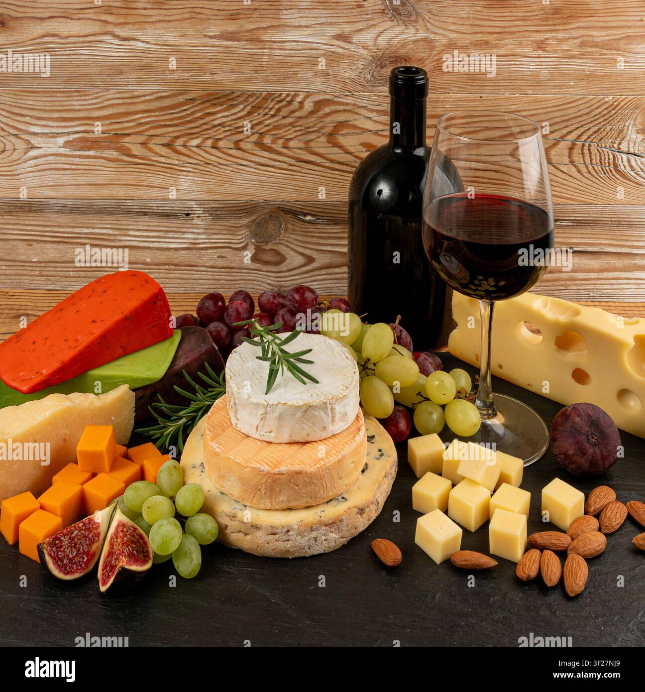 Piatto di formaggi vari colorati, piatto di gorgonzola giallo, bianco e blu con bicchiere di vino rosso, tagliere di formaggi, prodotti caseari tritati assortiti, m Foto Stock
