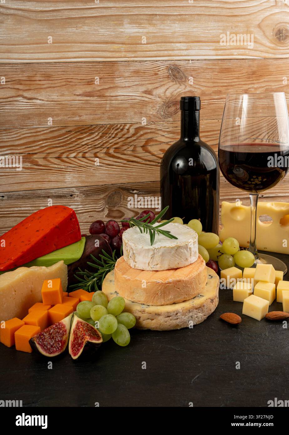Piatto di formaggi vari colorati, piatto di gorgonzola giallo, bianco e blu con bicchiere di vino rosso, tagliere di formaggi, prodotti caseari tritati assortiti, m Foto Stock