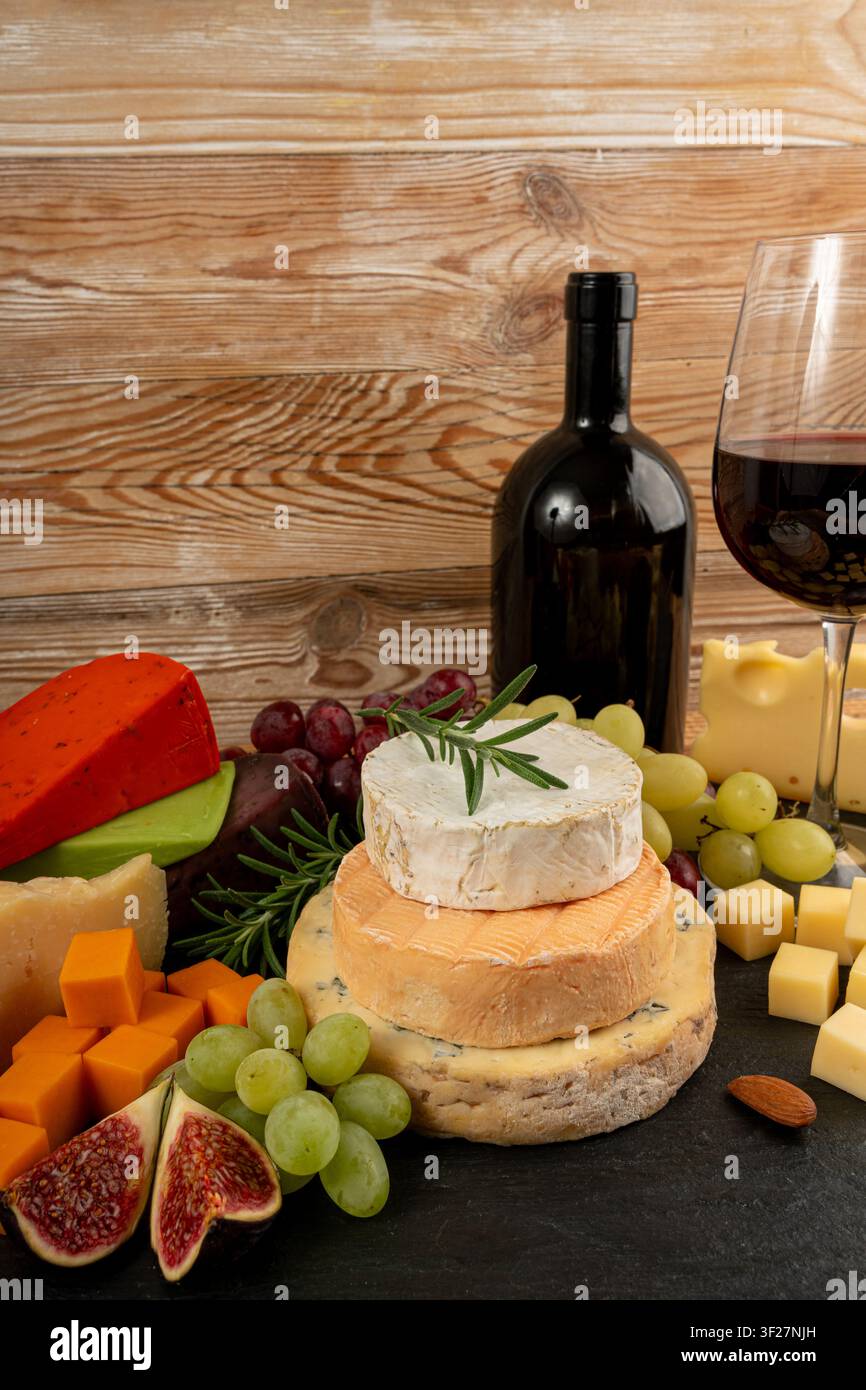 Piatto di formaggi vari colorati, piatto di gorgonzola giallo, bianco e blu con bicchiere di vino rosso, tagliere di formaggi, prodotti caseari tritati assortiti, m Foto Stock