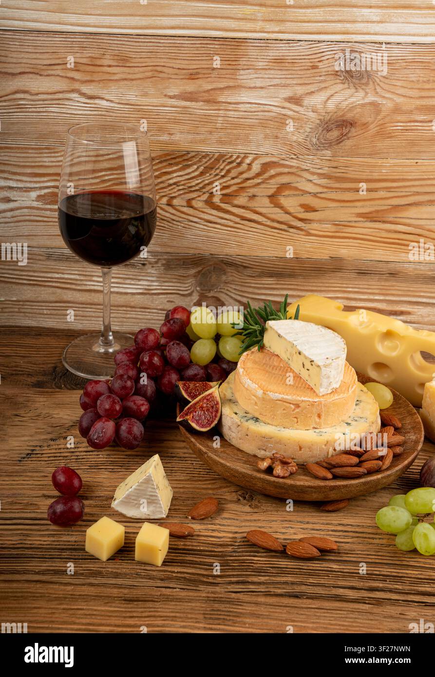 Piatto di formaggi vari colorati, piatto di gorgonzola giallo, bianco e blu con bicchiere di vino rosso, tagliere di formaggi, prodotti caseari tritati assortiti, m Foto Stock