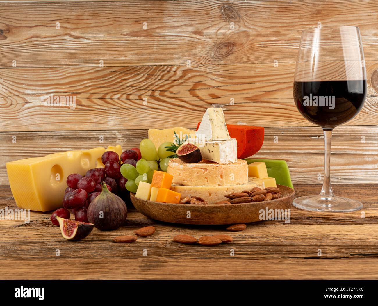 Piatto di formaggi vari colorati, piatto di gorgonzola giallo, bianco e blu con bicchiere di vino rosso, tagliere di formaggi, prodotti caseari tritati assortiti, m Foto Stock