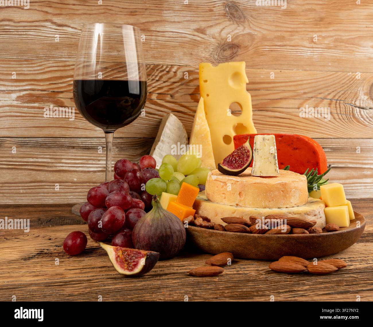 Piatto di formaggi vari colorati, piatto di gorgonzola giallo, bianco e blu con bicchiere di vino rosso, tagliere di formaggi, prodotti caseari tritati assortiti, m Foto Stock