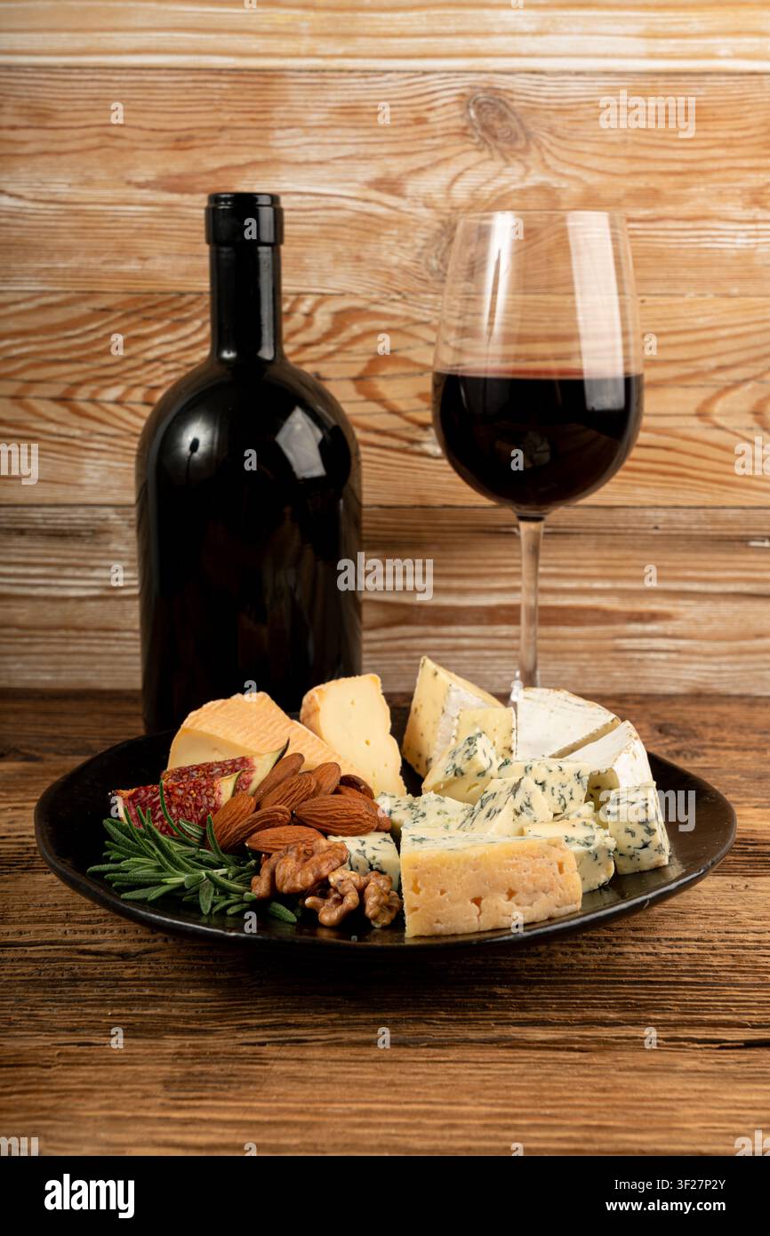 Piatto di formaggi vari colorati, piatto di gorgonzola giallo, bianco e blu con bicchiere di vino rosso, tagliere di formaggi, prodotti caseari tritati assortiti, m Foto Stock