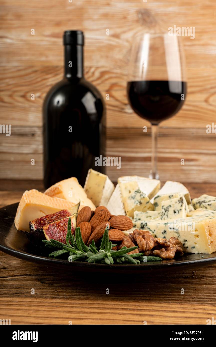Piatto di formaggi vari colorati, piatto di gorgonzola giallo, bianco e blu con bicchiere di vino rosso, tagliere di formaggi, prodotti caseari tritati assortiti, m Foto Stock
