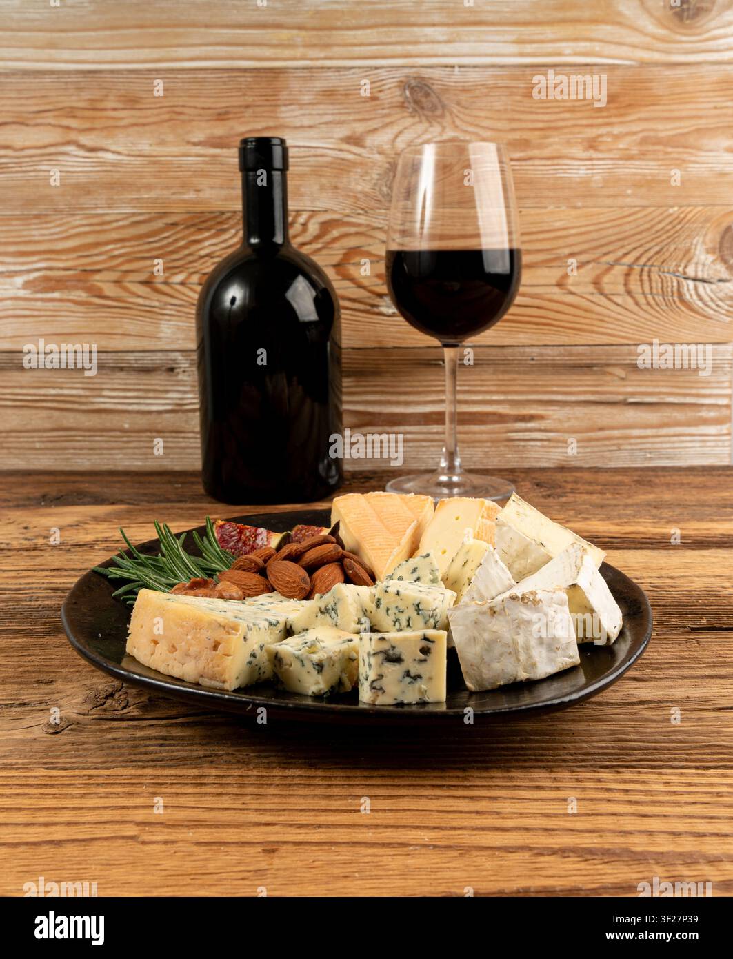 Piatto di formaggi vari colorati, piatto di gorgonzola giallo, bianco e blu con bicchiere di vino rosso, tagliere di formaggi, prodotti caseari tritati assortiti, m Foto Stock