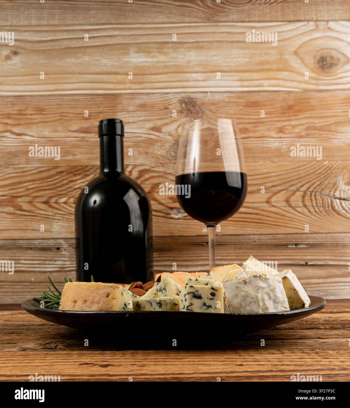 Piatto di formaggi vari colorati, piatto di gorgonzola giallo, bianco e blu con bicchiere di vino rosso, tagliere di formaggi, prodotti caseari tritati assortiti, m Foto Stock
