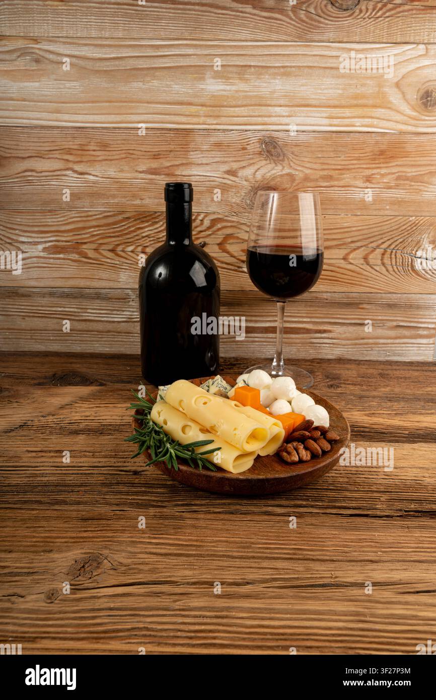 Piatto di formaggi vari colorati, piatto di gorgonzola giallo, bianco e blu con bicchiere di vino rosso, tagliere di formaggi, prodotti caseari tritati assortiti, m Foto Stock