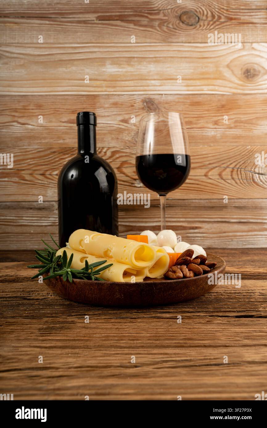 Piatto di formaggi vari colorati, piatto di gorgonzola giallo, bianco e blu con bicchiere di vino rosso, tagliere di formaggi, prodotti caseari tritati assortiti, m Foto Stock