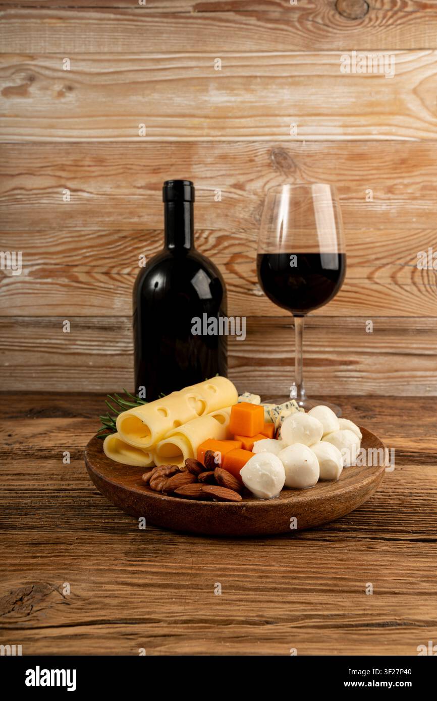 Piatto di formaggi vari colorati, piatto di gorgonzola giallo, bianco e blu con bicchiere di vino rosso, tagliere di formaggi, prodotti caseari tritati assortiti, m Foto Stock