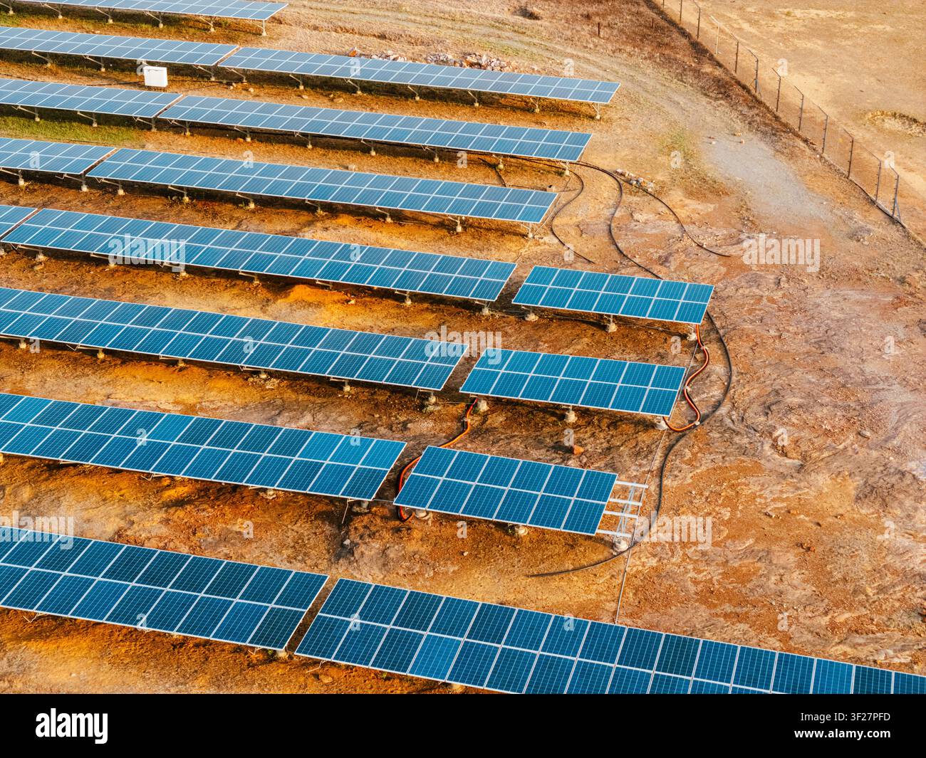 Vista a droni di un campo solare con cavi elettrici in una struttura per energie rinnovabili Foto Stock