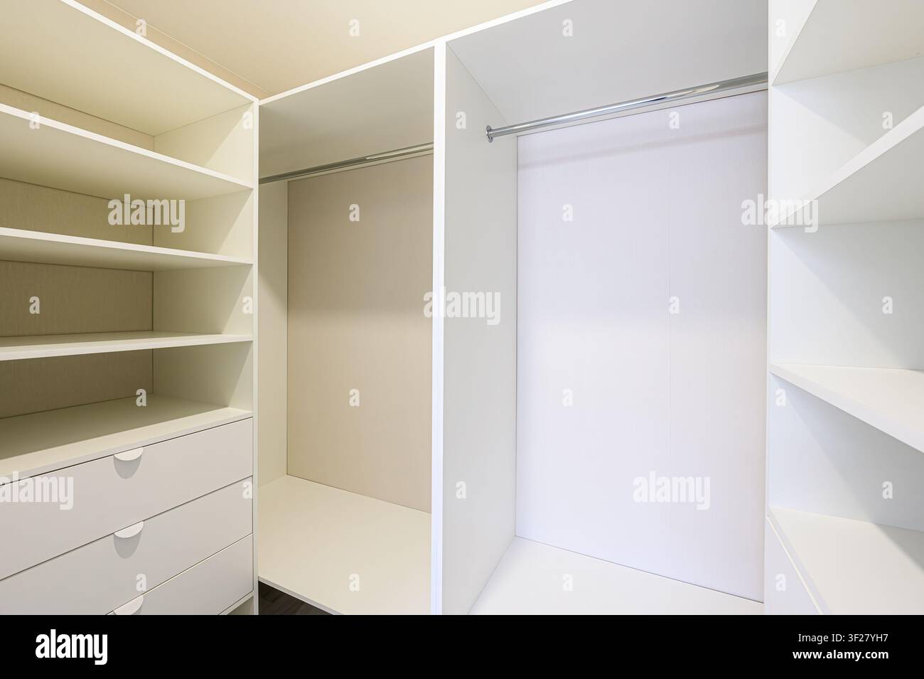 interno di guardaroba pulito e moderno. Presenta scaffali, cassetti e aste per appendere bianchi, con spazi vuoti, suggerendo organizzazione e archiviazione Foto Stock