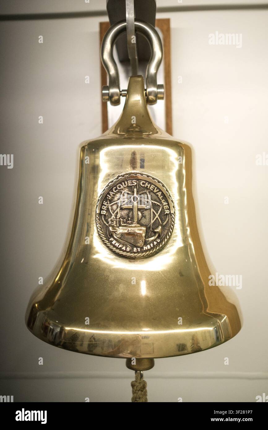 Vista interna ravvicinata di una campana navale in ottone con l'emblema di Jacques Chevallier e il motto Terra et Mare a bordo della forza di rifornimento della Marina francese Foto Stock