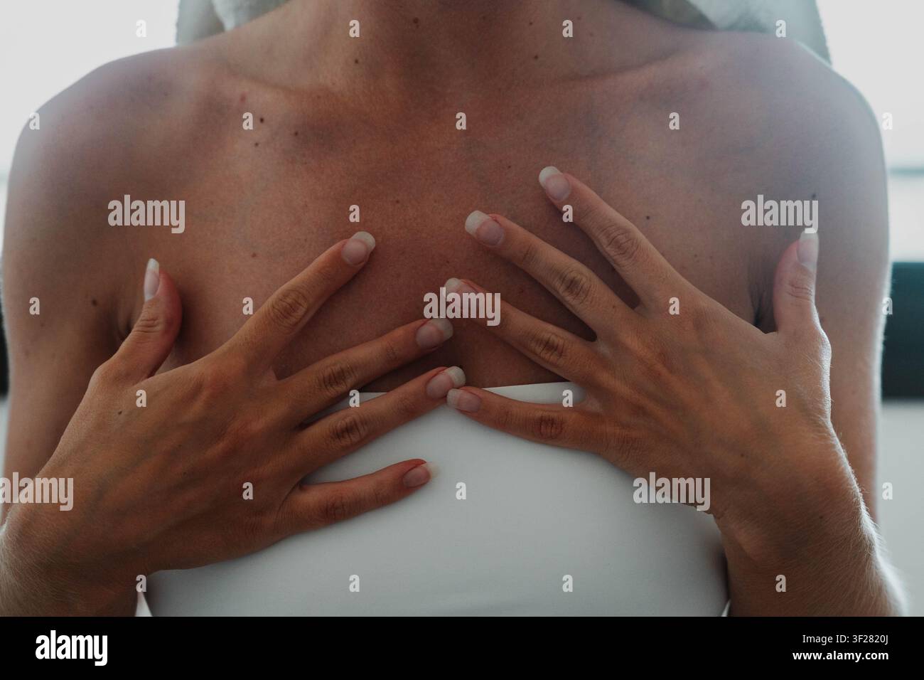 Donna che riposa entrambe le mani sulla parte superiore del petto con una postura naturale e rilassata. La consapevolezza del corpo promuove la mindfulness, abitudini salutari e benessere quotidiano Foto Stock