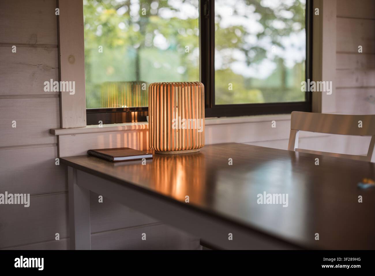 Luce calda in legno che brilla su una scrivania accanto a una finestra Foto Stock