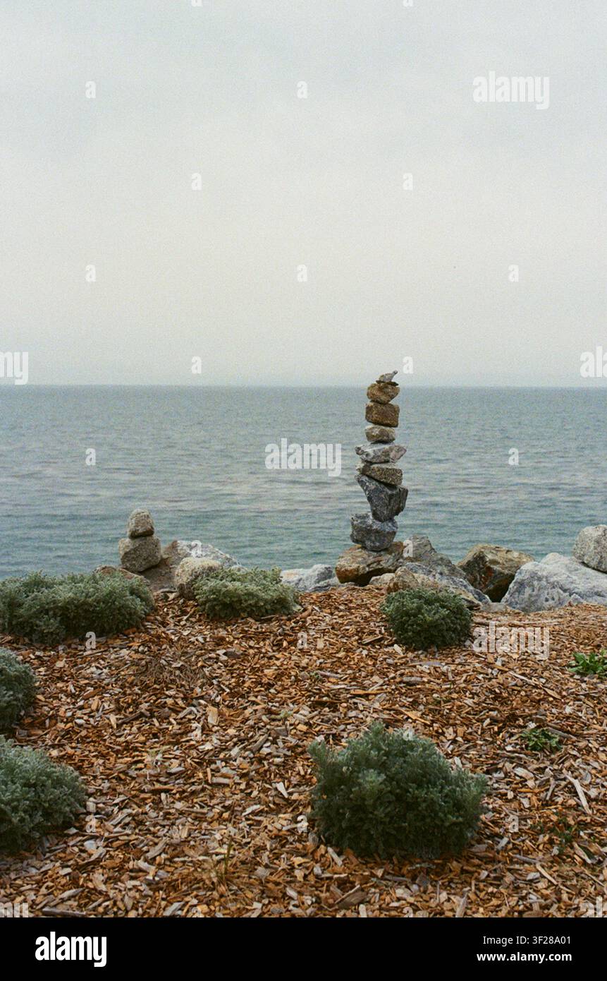 Cairne rocciosa vicino a una scogliera sull'oceano in una mattina nebbiosa Foto Stock
