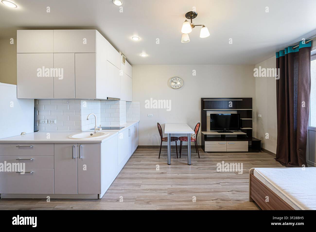 monolocale ben illuminato con cucina moderna, zona pranzo e centro multimediale con TV Foto Stock