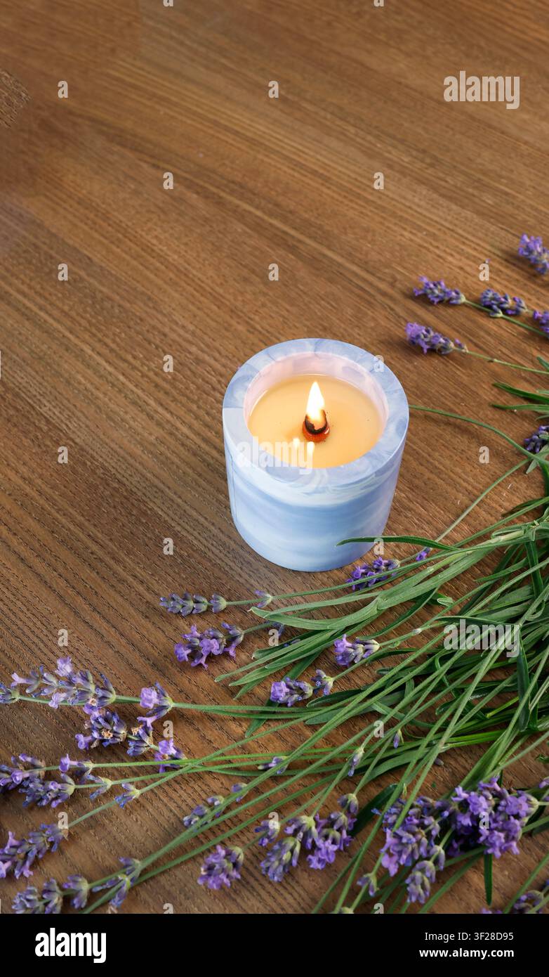 Candela accesa in barattolo di ceramica blu mazzo di fiori di lavanda fresca piano di tavolo vista dall'alto. Cornice verticale spazio di copia vuoto modello di testo pubblicità Foto Stock