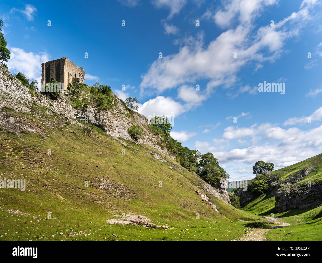 Le rovine storiche del castello di Peveril si ergono in modo prominente su una ripida cresta rocciosa che si affaccia sulla valle calcarea di Cave Dale nel Derbyshire, Regno Unito Foto Stock