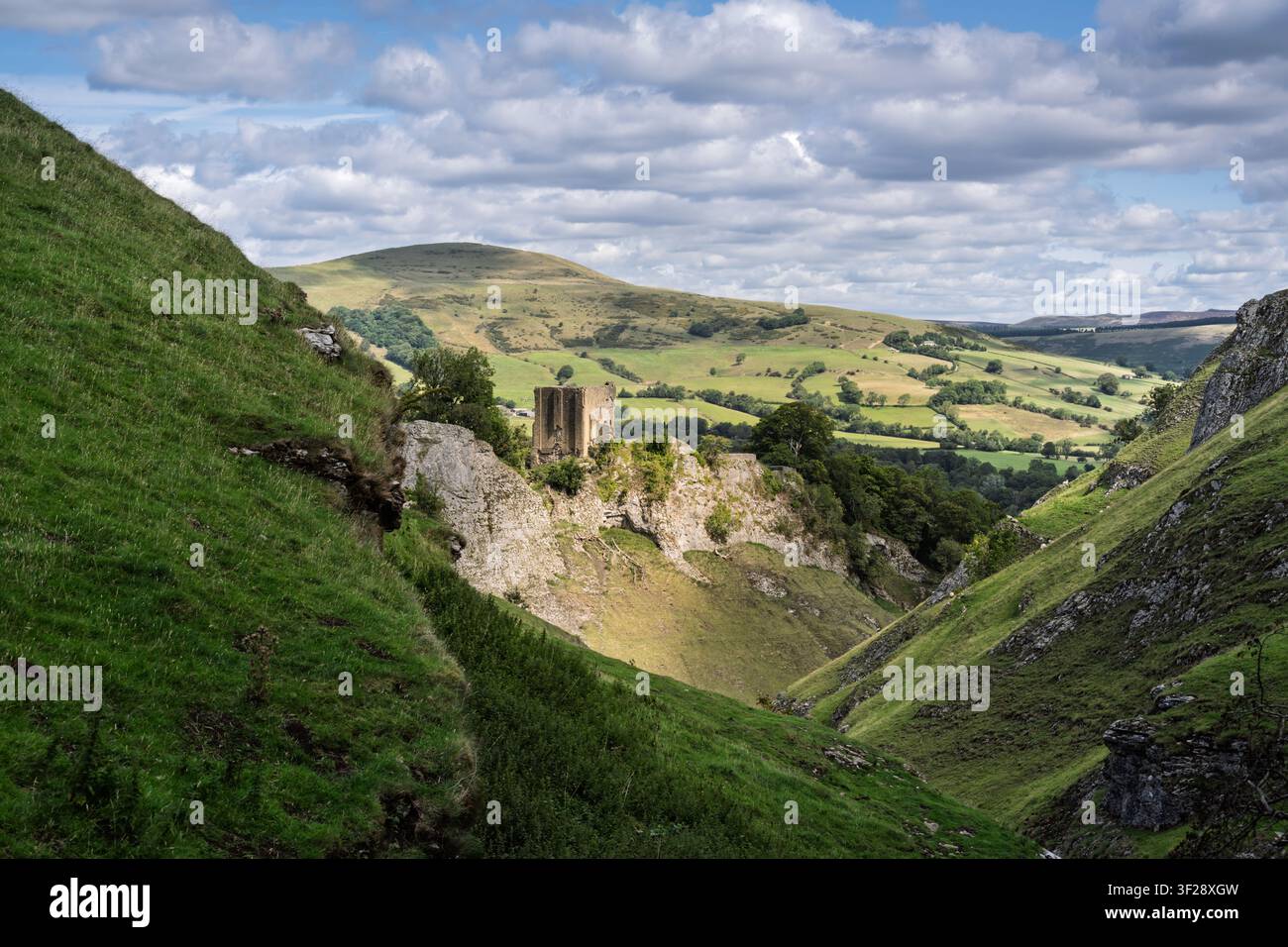 Una vista elevata dalle alte pendici di Cave Dale che guarda giù oltre il castello di Peveril verso i campi a chiazze della lontana Hope Valley, UK Foto Stock