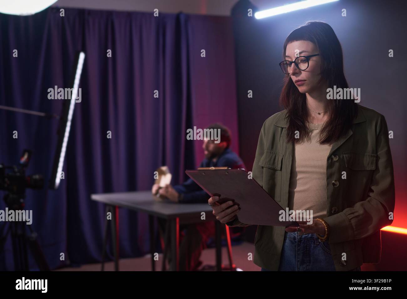 Donna che controlla la lista delle riprese sul set di produzione video Foto Stock