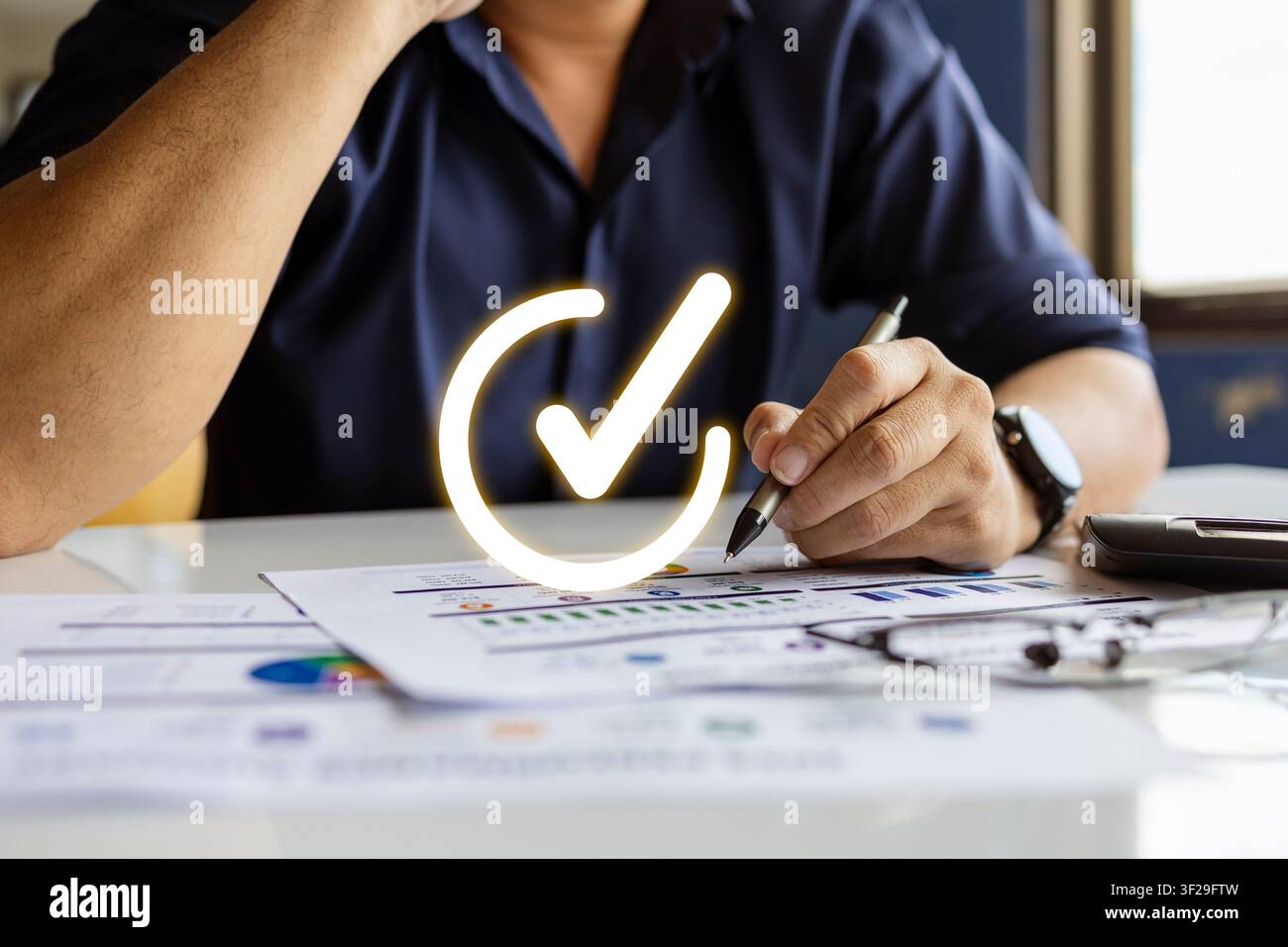 Uomo d'affari che esamina rapporti finanziari con un segno di approvazione, rappresentando audit, conformità e successo aziendale. Foto Stock