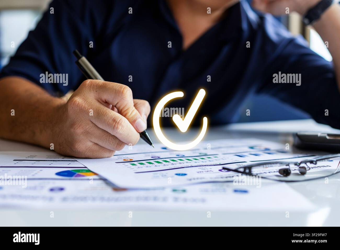 Uomo d'affari che esamina rapporti finanziari con un segno di approvazione, rappresentando audit, conformità e successo aziendale. Foto Stock