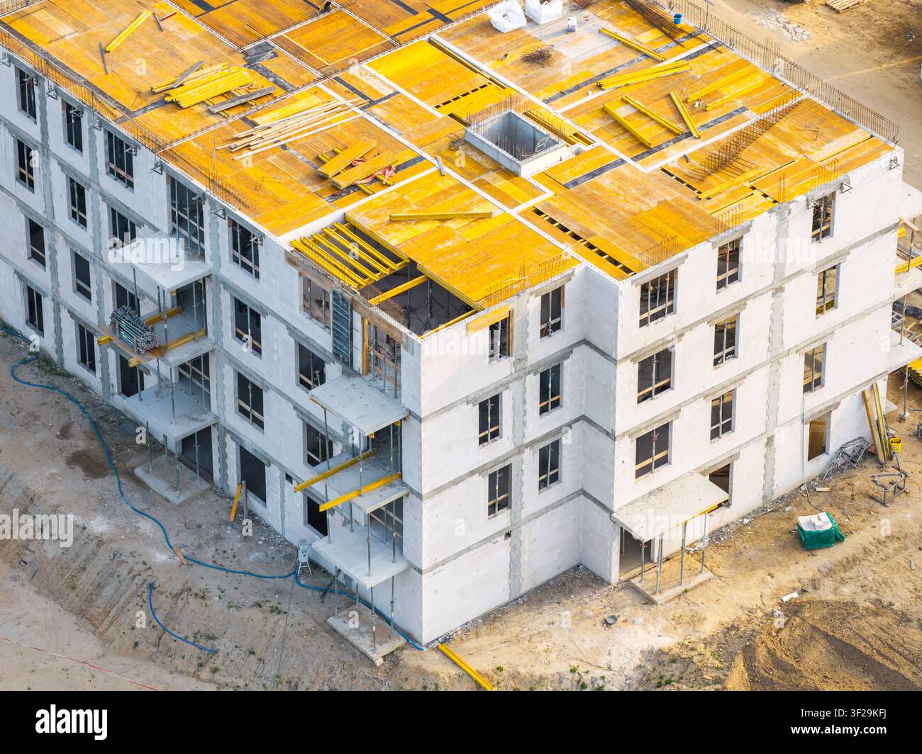 Vista aerea di un edificio residenziale in costruzione con gettatoi del tetto gialli e pareti in cemento bianco a Kowale, Voivodato della Pomerania, Polonia. Foto Stock