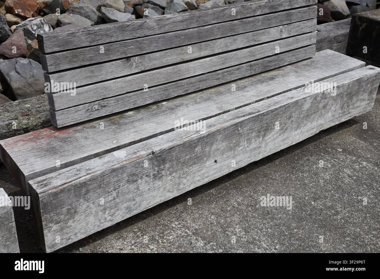 panca da esterno robusta e consumata costruita con travi in legno duro riciclato recuperate da strutture storiche di moli (primo piano) Foto Stock