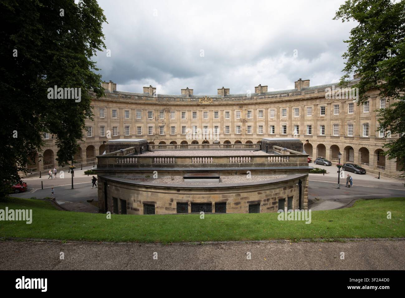 La grandiosa architettura georgiana del Buxton Crescent sotto un cielo drammatico, vista dalla passeggiata rialzata del parco Slopes a Buxton, Derbyshire, Regno Unito. Foto Stock