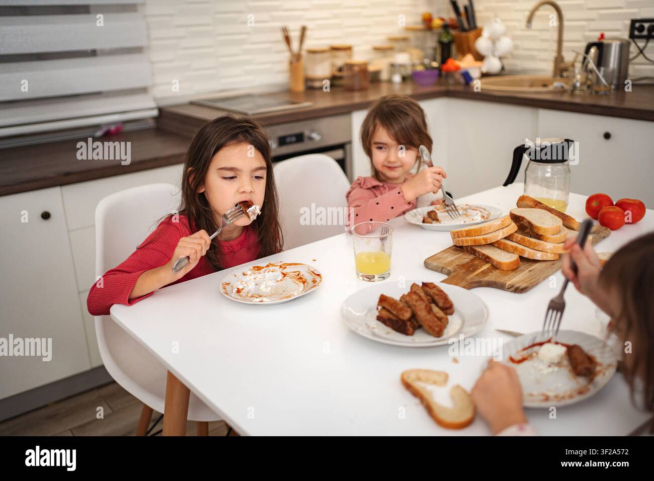 I bambini fanno colazione in cucina e si godono i pasti in famiglia Foto Stock