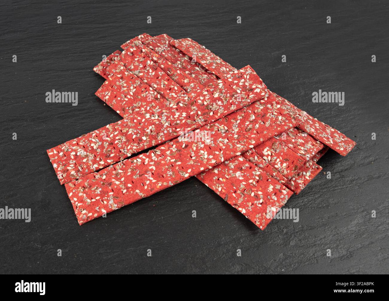Cracker alla barbabietola, pane rusk sottile alla barbabietola rossa, pane croccante multigrain rosso dietetico, pane croccante ai semi integrali vari, cracker lungo al sesamo, girasole Foto Stock